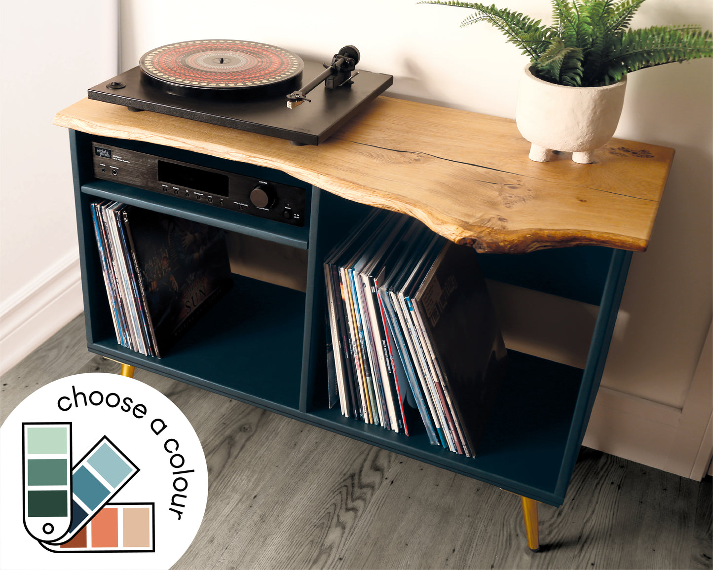Front view of a vinyl record player cabinet featuring a live edge solid oak top, two compartments for vinyl storage, an amp shelf on one side, and gold tapered metal legs.