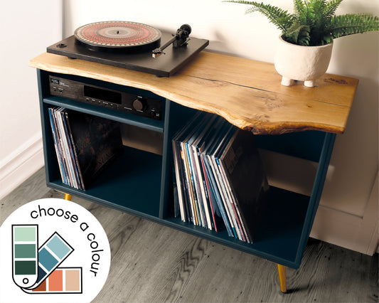 Front view of a vinyl record player cabinet featuring a live edge solid oak top, two compartments for vinyl storage, an amp shelf on one side, and gold tapered metal legs.