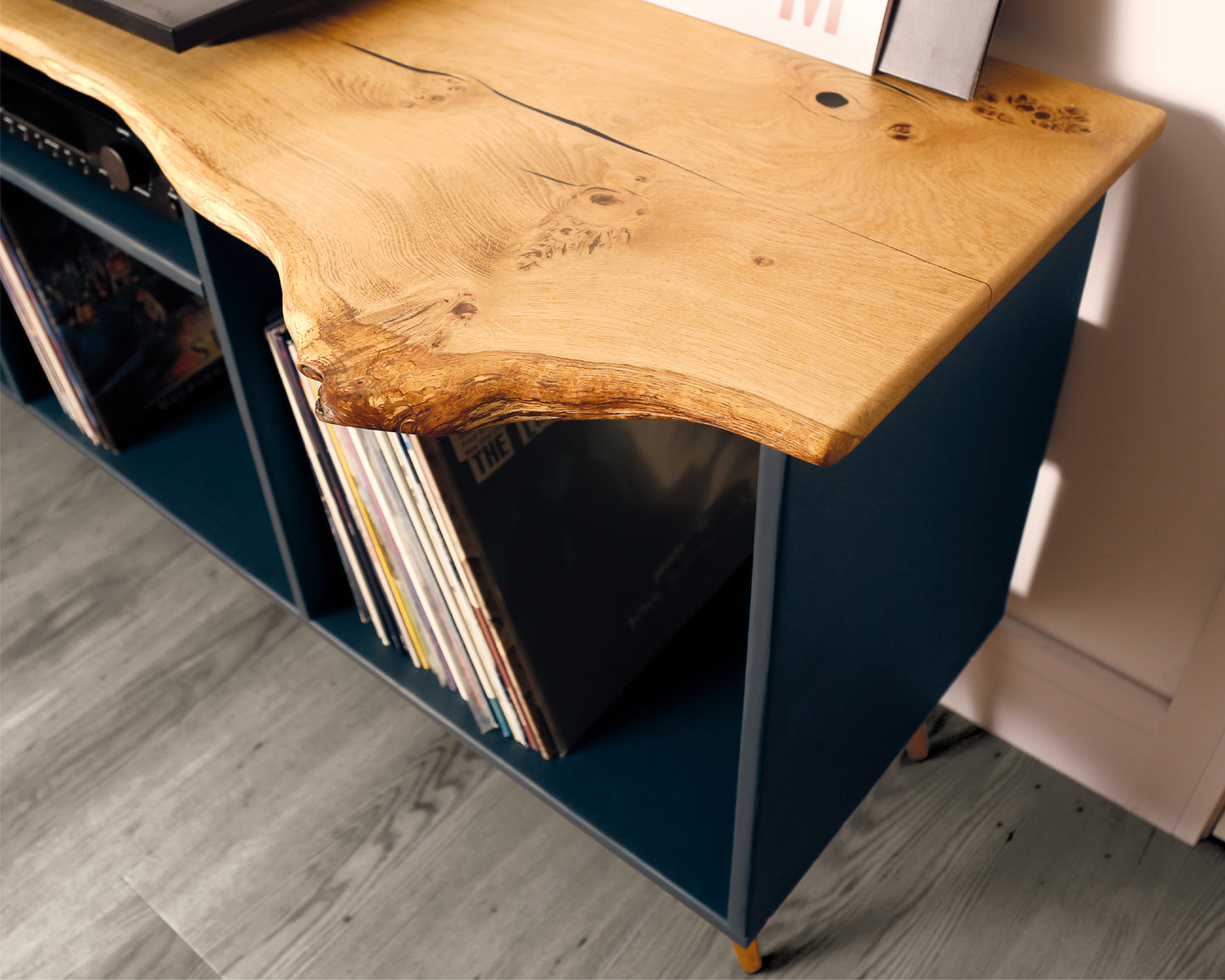 High-angle view of a vinyl record player cabinet, focusing on the live edge solid oak top, rich wood grain, and smooth natural finish, highlighting its craftsmanship and organic character.