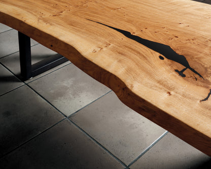 Close-up of live edge oak coffee table with natural waney edges, black resin filler, and stunning wood grain. A perfect blend of nature and style.